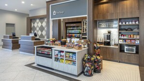 Eine Hotlellobby mit Café-Bereich, einer Rezeption und einem Automaten.