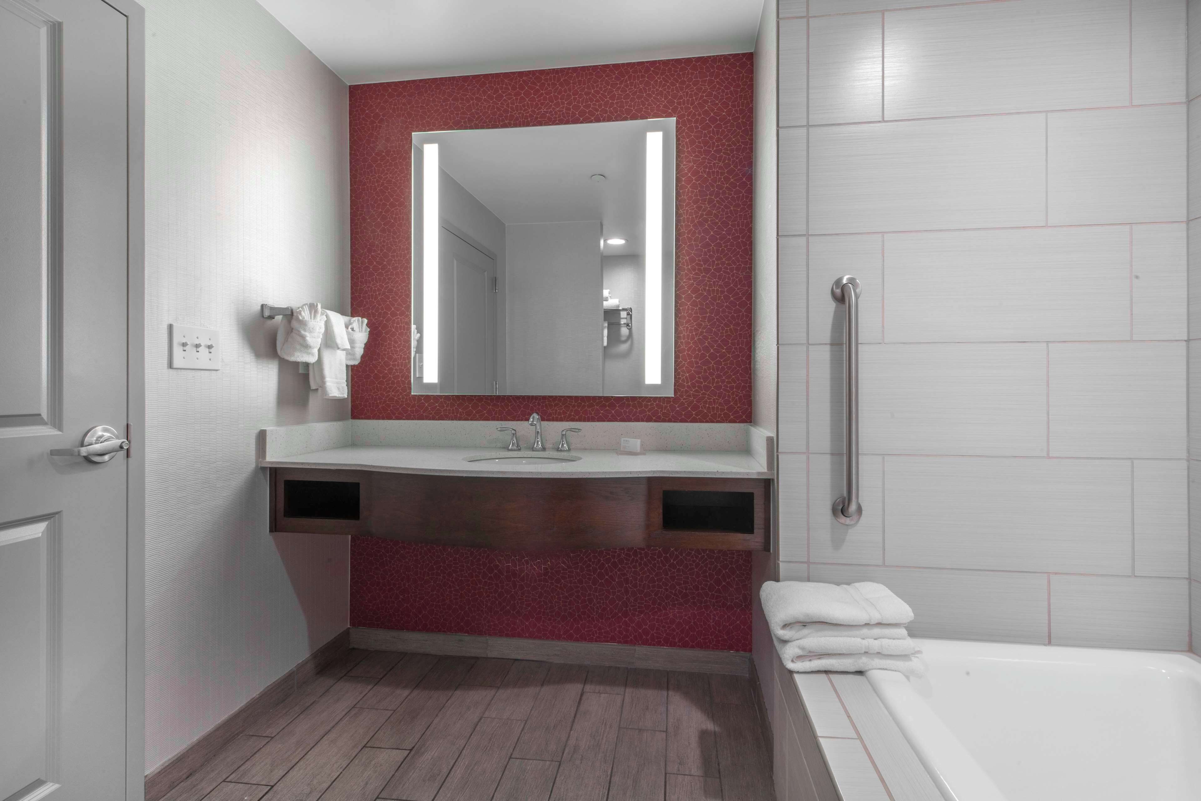 Un baño con espejo, lavabo y bañera.