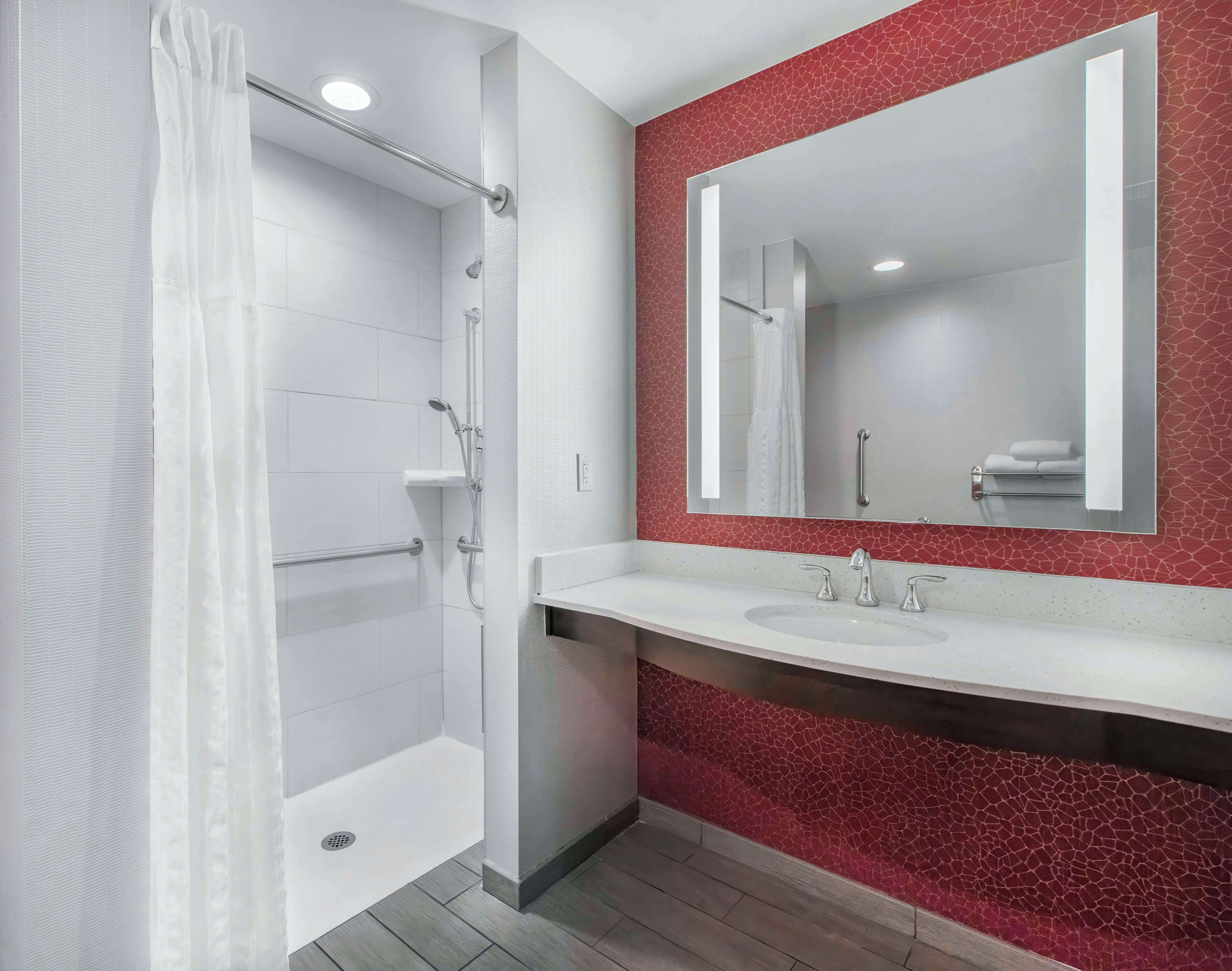 A modern bathroom with a shower, a sink, and a large mirror.