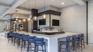 Eine moderne Bar mit einer langen Theke, mehreren Barhocker und hängenden Pendelleuchten.
