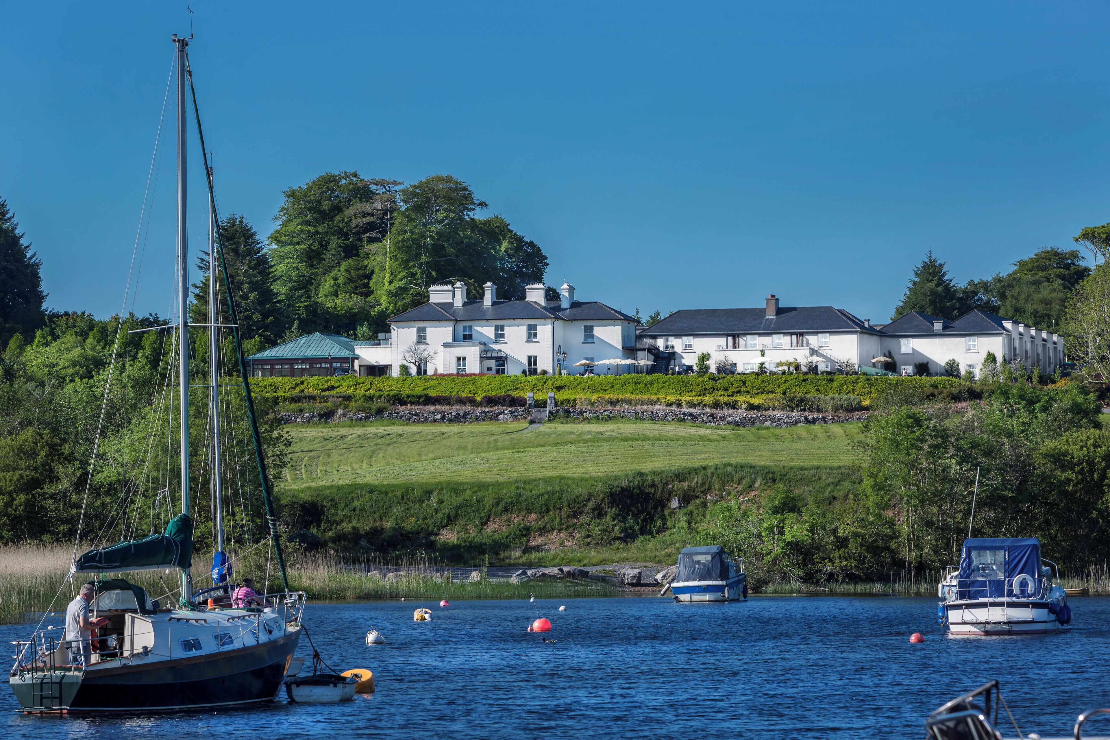 A waterfront property with a large house, boats, and a sailboat.