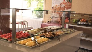 Un bufé con diferentes opciones de comida, incluyendo sandía, queso y pasteles.