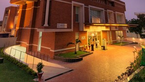 Un hotel de varios pisos con fachada de ladrillo, ventanas amplias y una entrada bien iluminada.