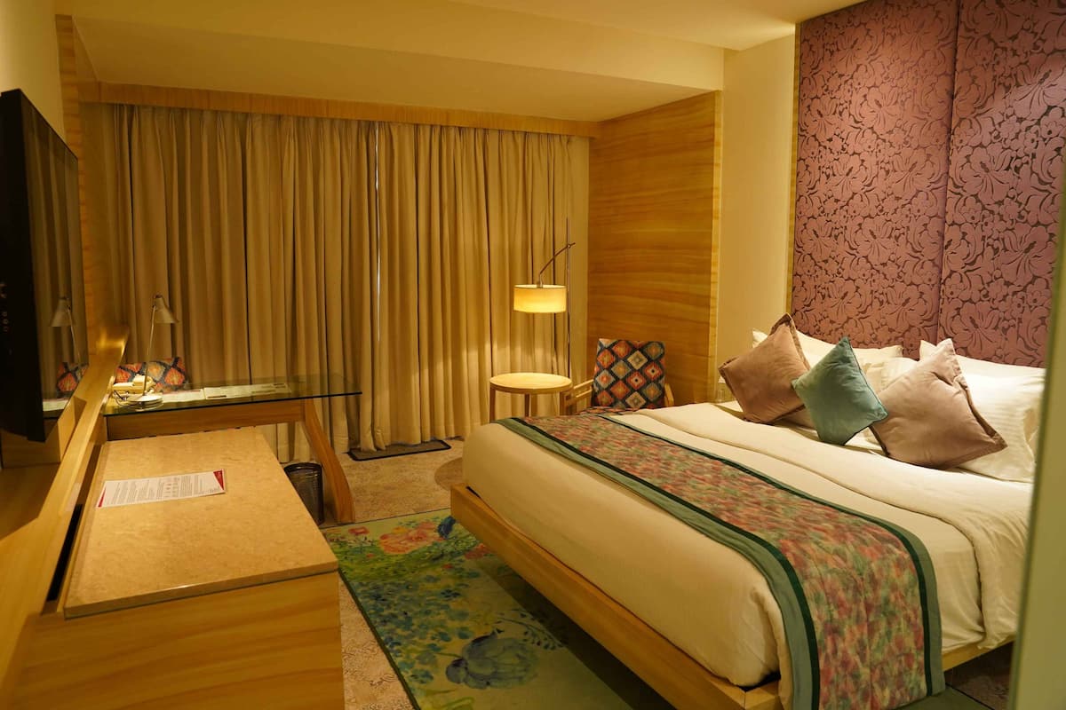Een hotelkamer met een bed, een bureau, een stoel, een lamp en een televisie.