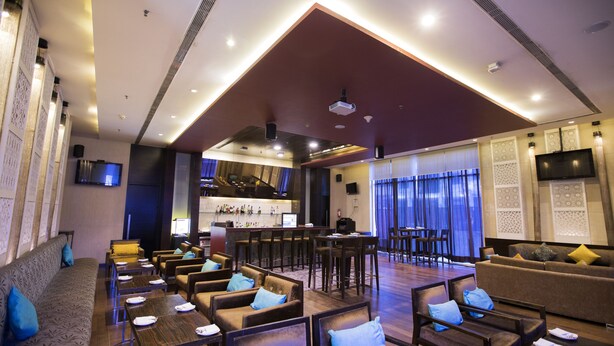 Un vestíbulo amplio con zona de bar, asientos y una pantalla grande.