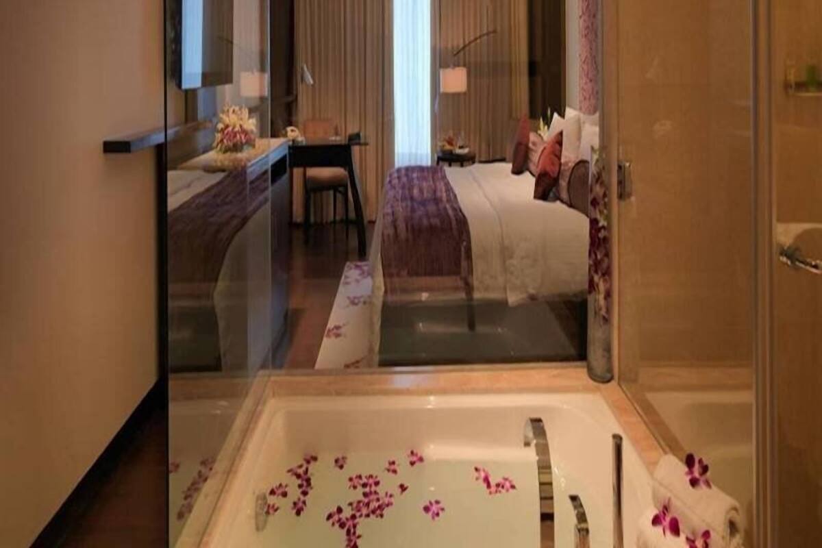 Een hotelkamer met een groot bad, een bed, een bureau en een stoel.