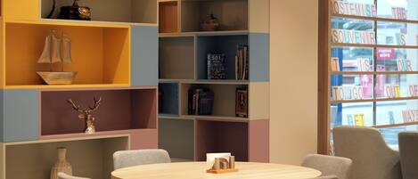 Una biblioteca acogedora con estantes coloridos, una mesa redonda de madera y asientos cómodos.