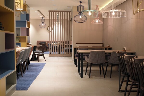 Un comedor moderno con una mesa larga, sillas y lámparas colgantes.