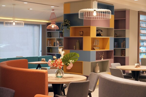 A modern interior with round tables, cushioned seating, and colorful shelving units. - Hampton by Hilton Ordu (Ordu)