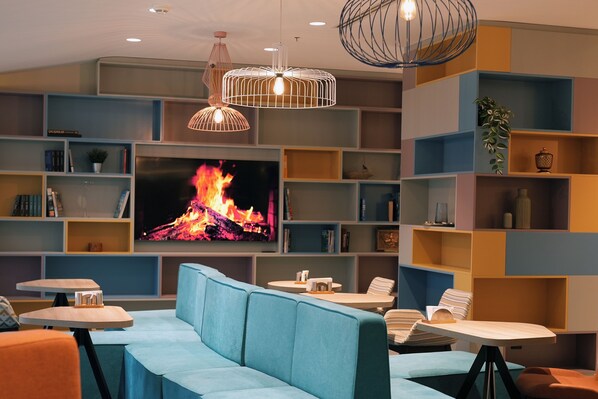 A modern living room with a fireplace, comfortable seating, and a large TV. - Hampton by Hilton Ordu (Ordu)