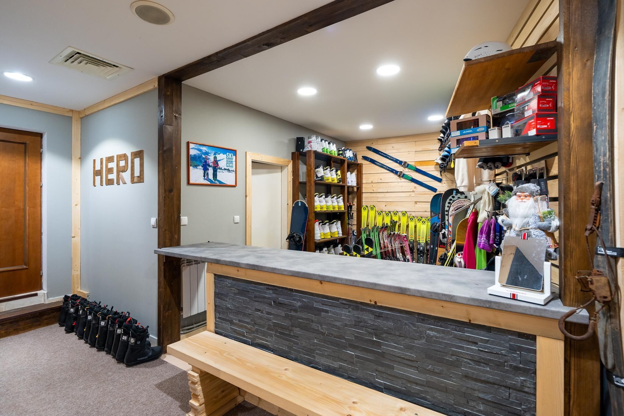 A ski lodge interior with a reception desk, ski equipment, and a 'HERO' sign on the wall.