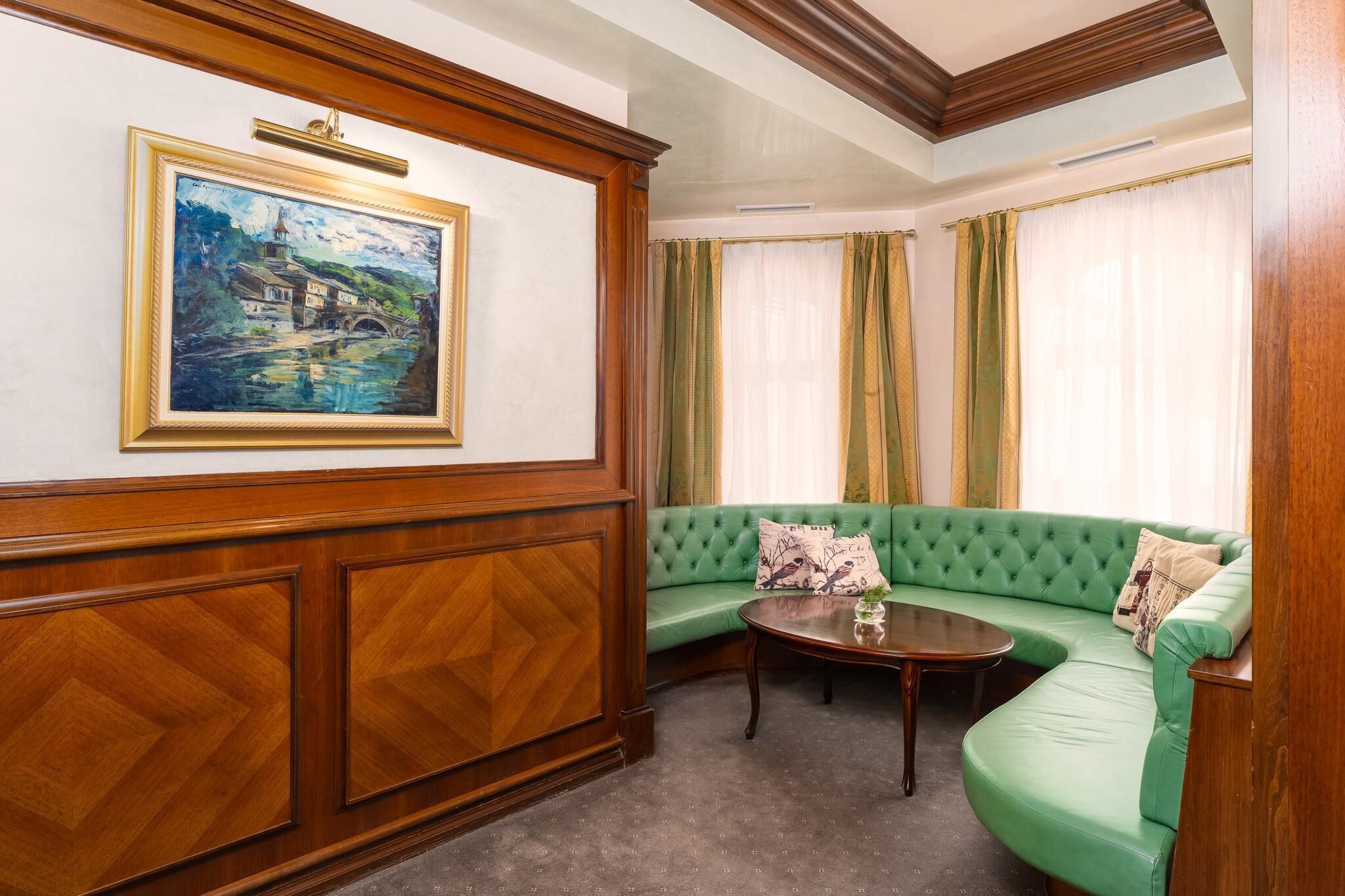 Una habitación con un sofá verde, un armario de madera, un cuadro y una ventana con cortinas.