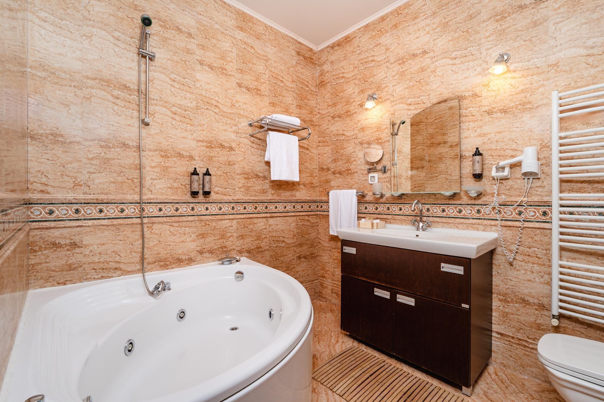 Ein Badezimmer mit freistehender Badewanne, einem Waschtisch mit Spiegel, einem Handtuchhalter und einer Toilette.