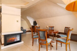 Uma sala de jantar com lareira, cadeiras de madeira e uma mesa redonda.