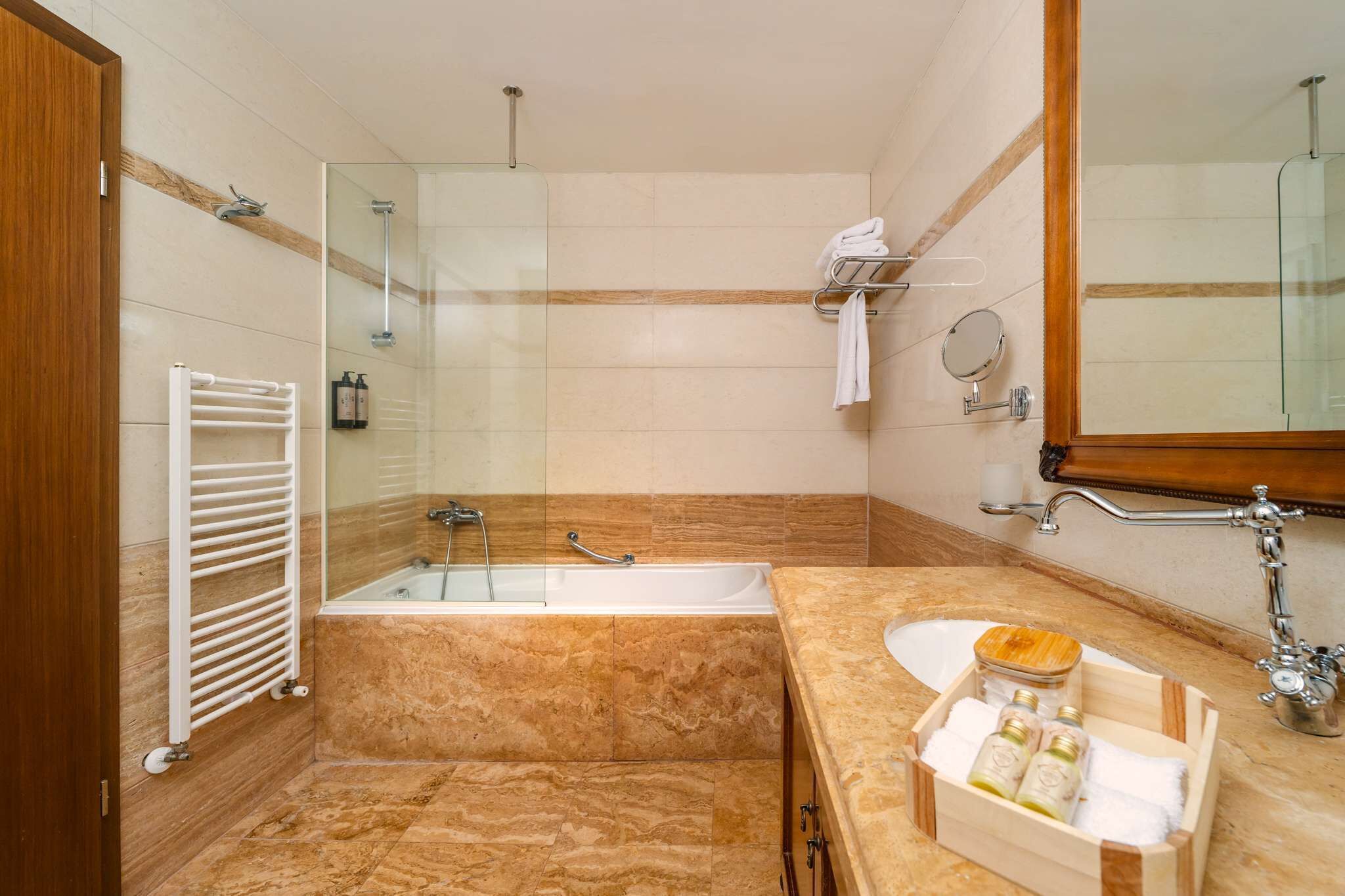 Un baño moderno con ducha de vidrio, bañera y tocador con lavamanos y espacio de almacenamiento.