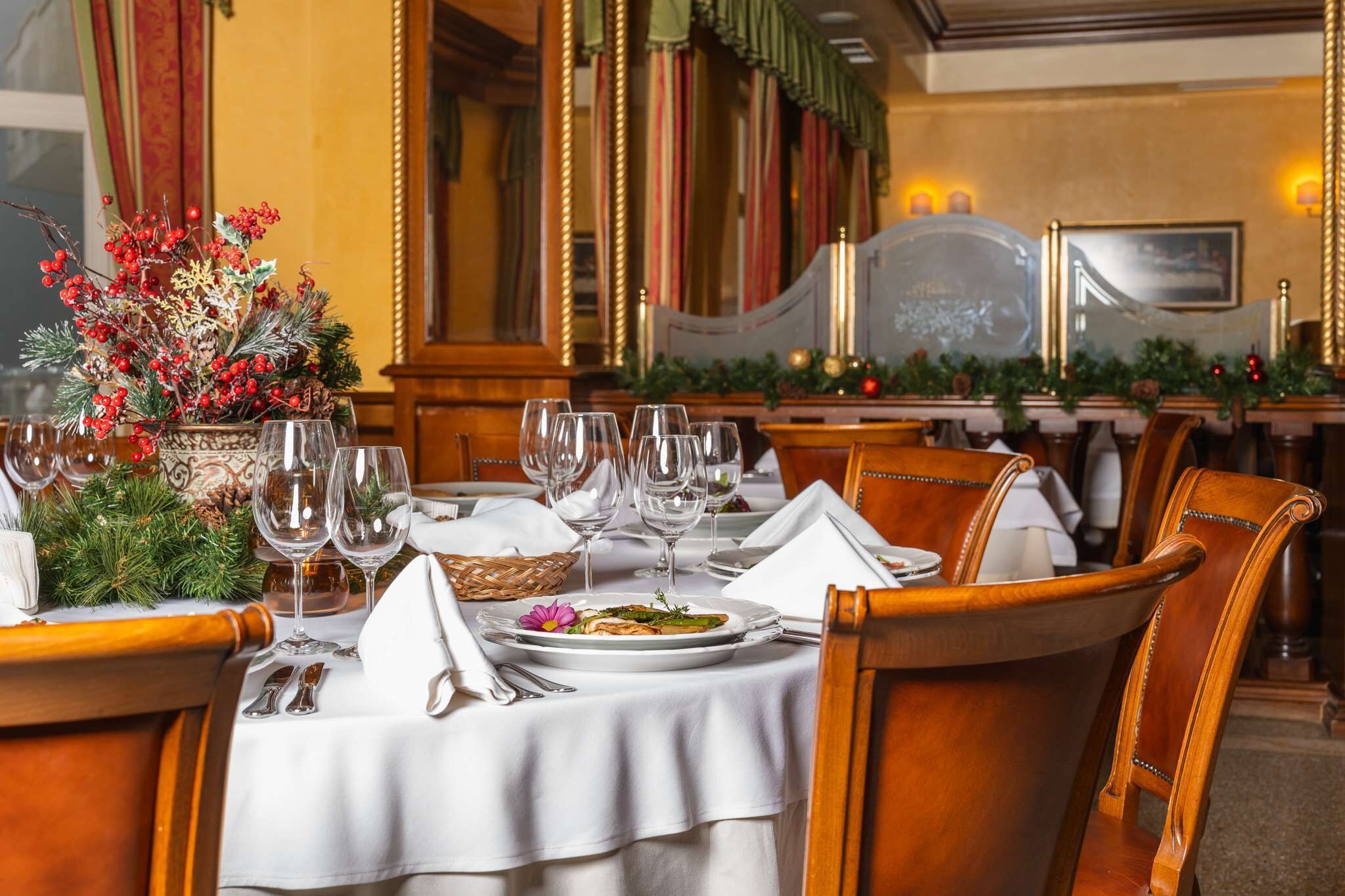 A dining table set with white tablecloth, plates, and wine glasses, surrounded by wooden chairs.