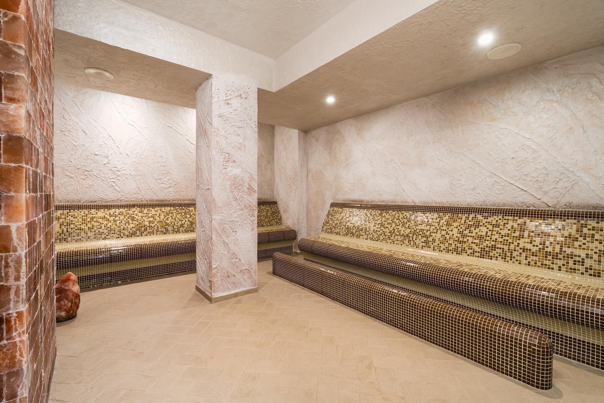 A spa area with mosaic-tiled benches and a brick column.