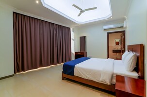 Una habitación de hotel con cama, escritorio, espejo y ventilador de techo.