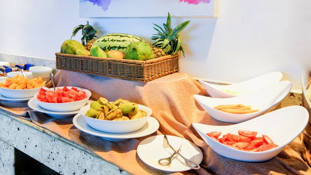 A buffet table with various fruits and a wicker basket containing fruits.