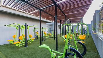An outdoor gym with exercise equipment, a covered area, and artificial grass.