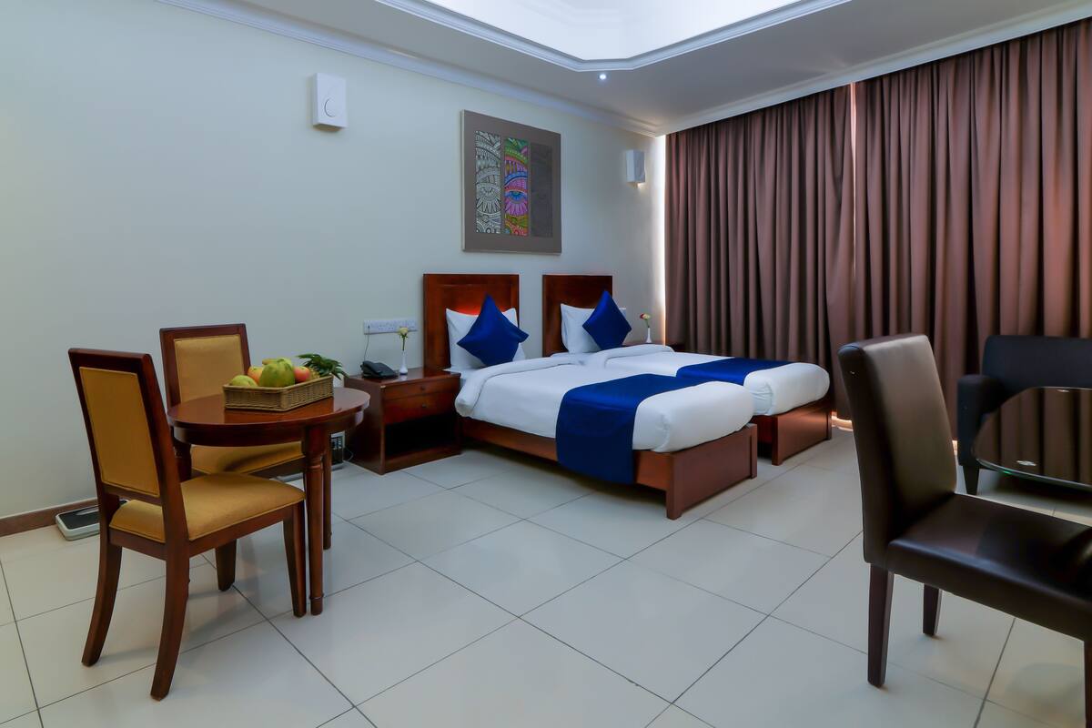 A hotel room with a bed, a desk, a chair, and a dining table.