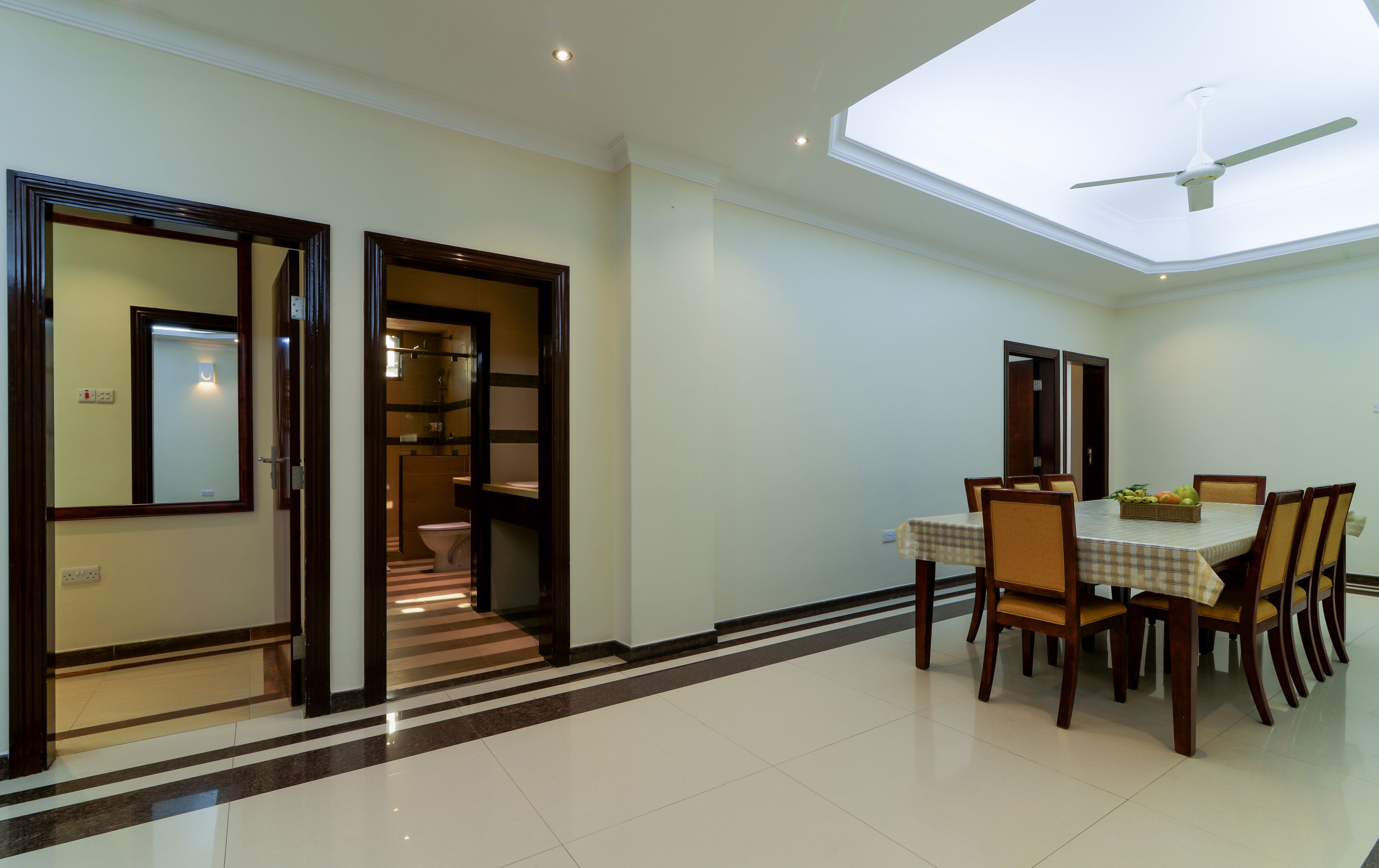 A dining area with a table and chairs, a ceiling fan, and a view of a bathroom through an open door.