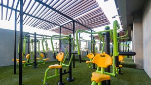 An outdoor gym with exercise equipment, a covered area, and artificial grass.