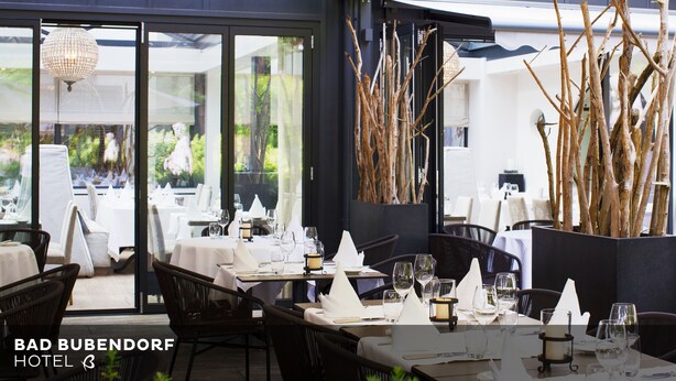 A restaurant setting with tables set for dining, including wine glasses and napkins. - Bad Bubendorf Hotel (Bubendorf)