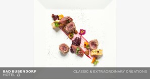 A gourmet dish with various ingredients and garnishes, presented on a white plate. - Bad Bubendorf Hotel (Bubendorf)