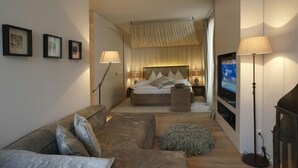 A modern bedroom with a bed, bedside tables, a TV, and a sofa. - Bad Bubendorf Hotel (Bubendorf)