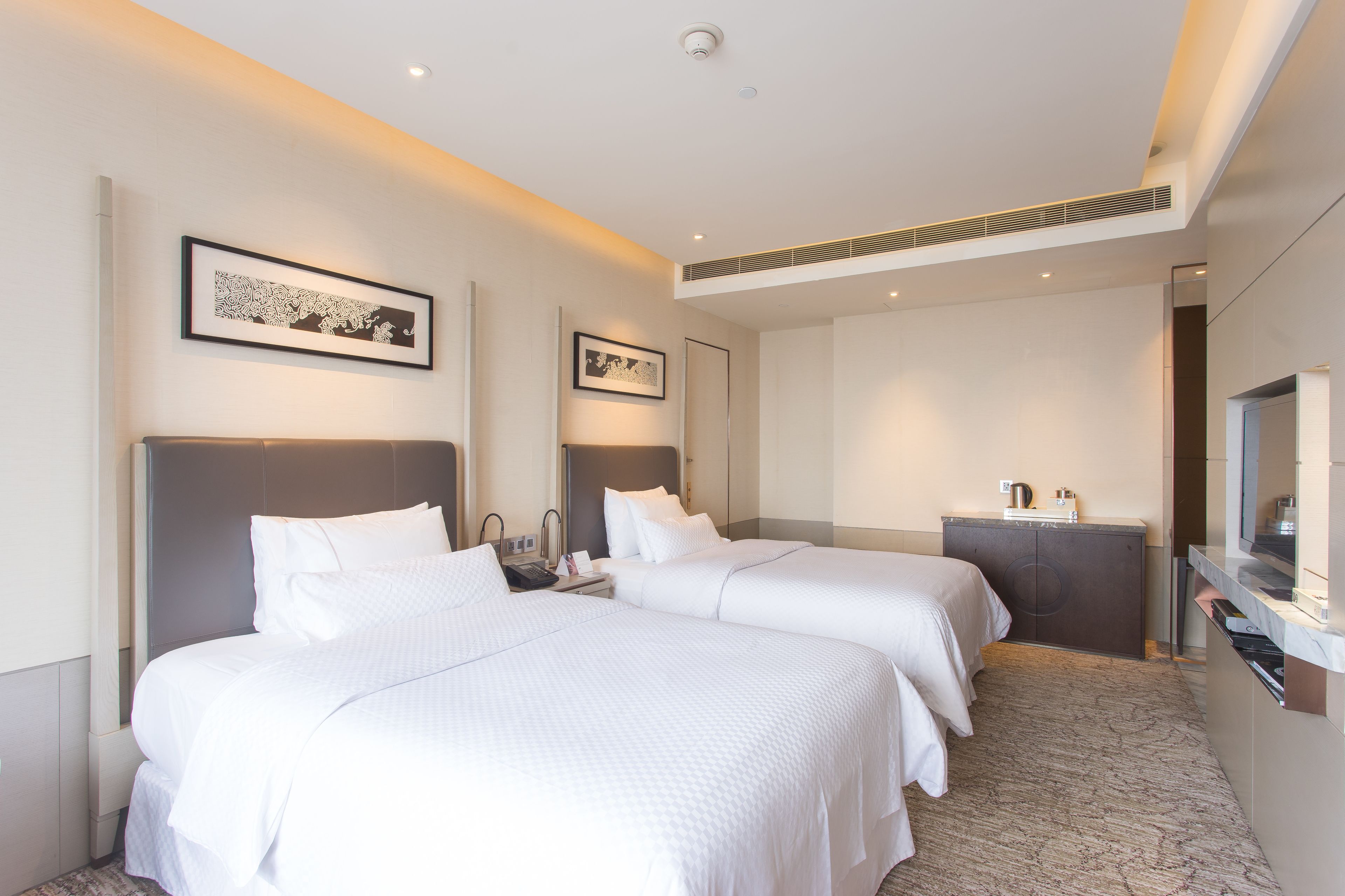 Een hotelkamer met twee bedden, een bureau, een dressoir en een televisie.