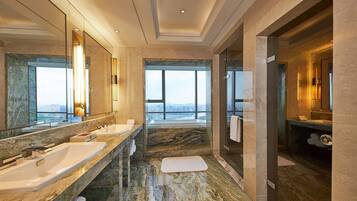 A modern bathroom with two sinks, a large mirror, and a view of the city.