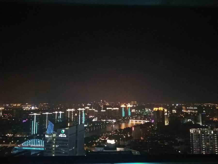 Un paisaje urbano nocturno con edificios iluminados y un puente.