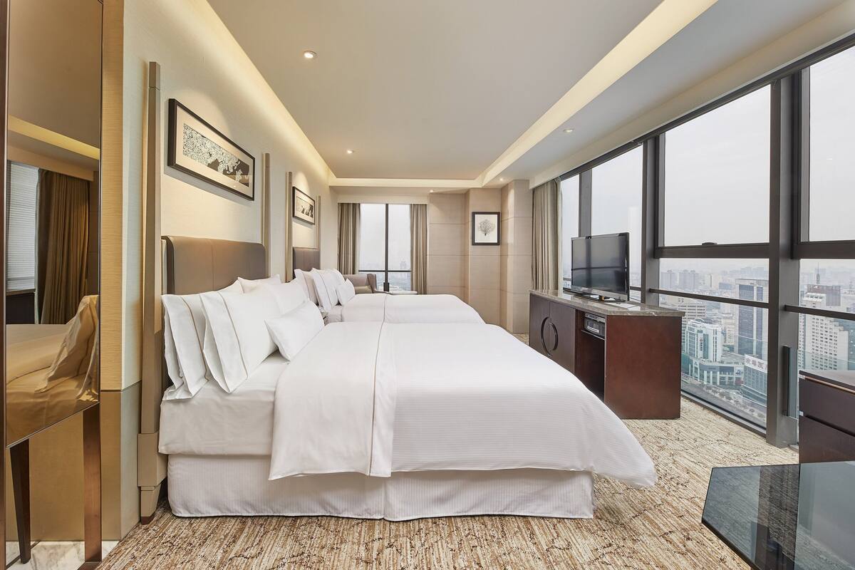 Une chambre d’hôtel moderne, dotée d’un grand lit, d’un bureau et d’une télévision.