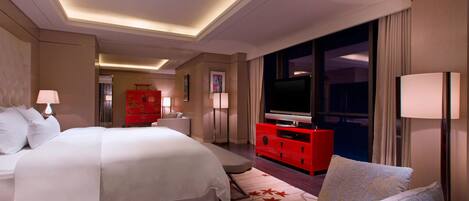 Una habitación de hotel con una cama grande, un aparador rojo, un televisor y un sofá.