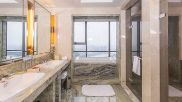 Ein modernes Badezimmer mit zwei Waschbecken, einer Badewanne und einem großen Fenster mit Blick auf die Stadt.