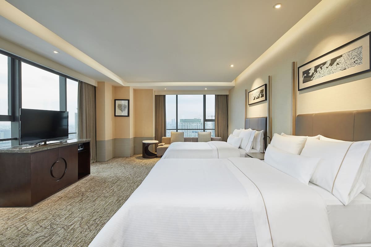 Une chambre d’hôtel avec deux lits, une télévision, un bureau et une vue sur la ville.
