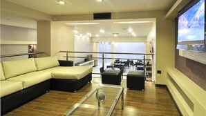 A modern lounge area with a sofa, ottoman, and a glass coffee table. - Amerian Salta Hotel (Salta)