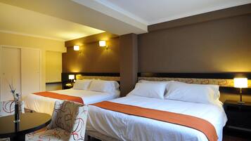 Habitación de hotel con dos camas, una mesa y una silla.
