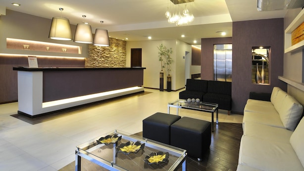A modern hotel lobby with a reception desk, seating area, and decorative lighting. - Amerian Salta Hotel (Salta)