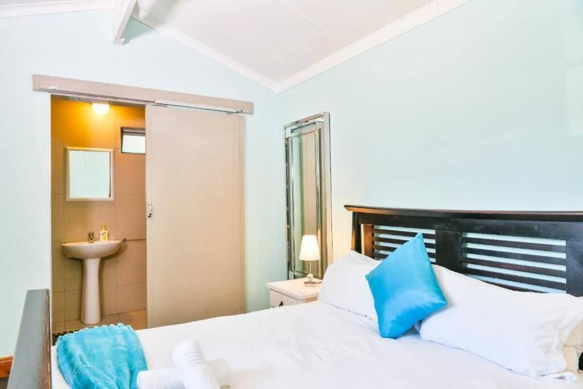 Ein Hotelzimmer mit Bett, Nachttisch, Spiegel und einem Badezimmer mit Waschbecken und Toilette.