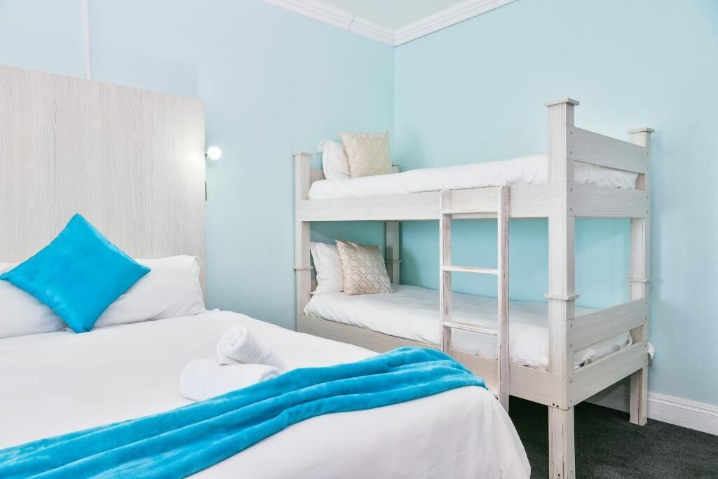 A room with a bunk bed, a single bed, and a wooden headboard.