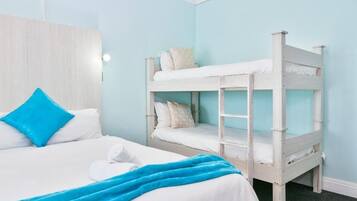 A room with a bunk bed, a single bed, and a wooden headboard.