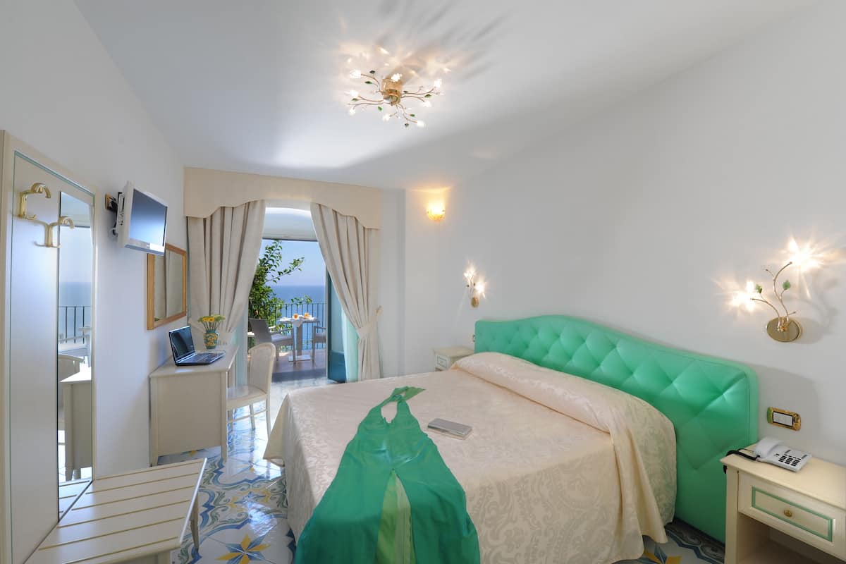 Une chambre d’hôtel avec un lit, un bureau avec un ordinateur portable, une table de chevet avec un téléphone et une vue sur l’extérieur.