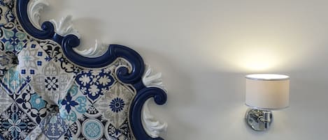 Un mur orné d’un motif décoratif bleu et blanc et un luminaire fixé au mur.