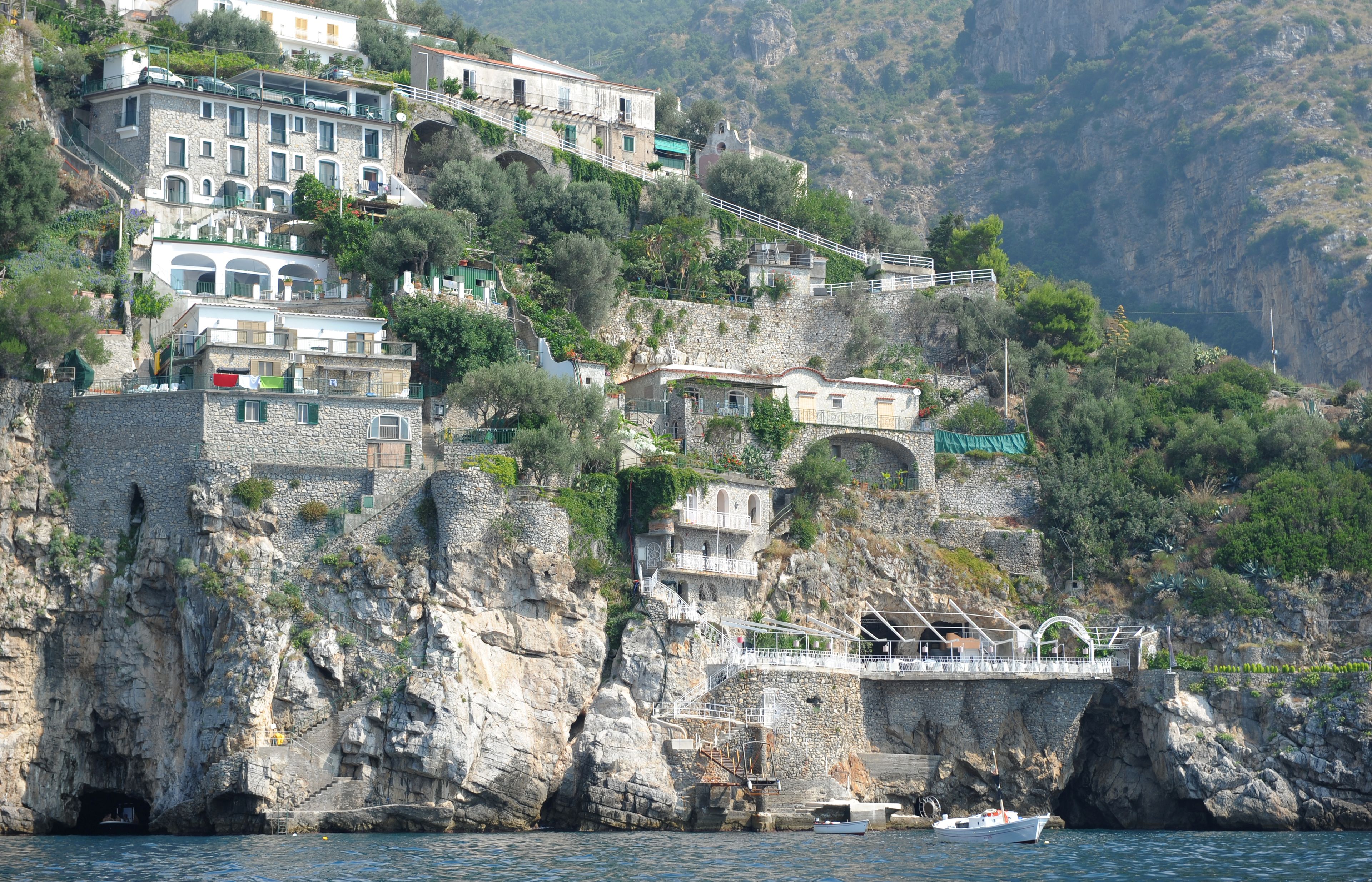 Un complejo de edificios costeros con varias estructuras, incluyendo un puente y una escalera que lleva a un nivel superior.