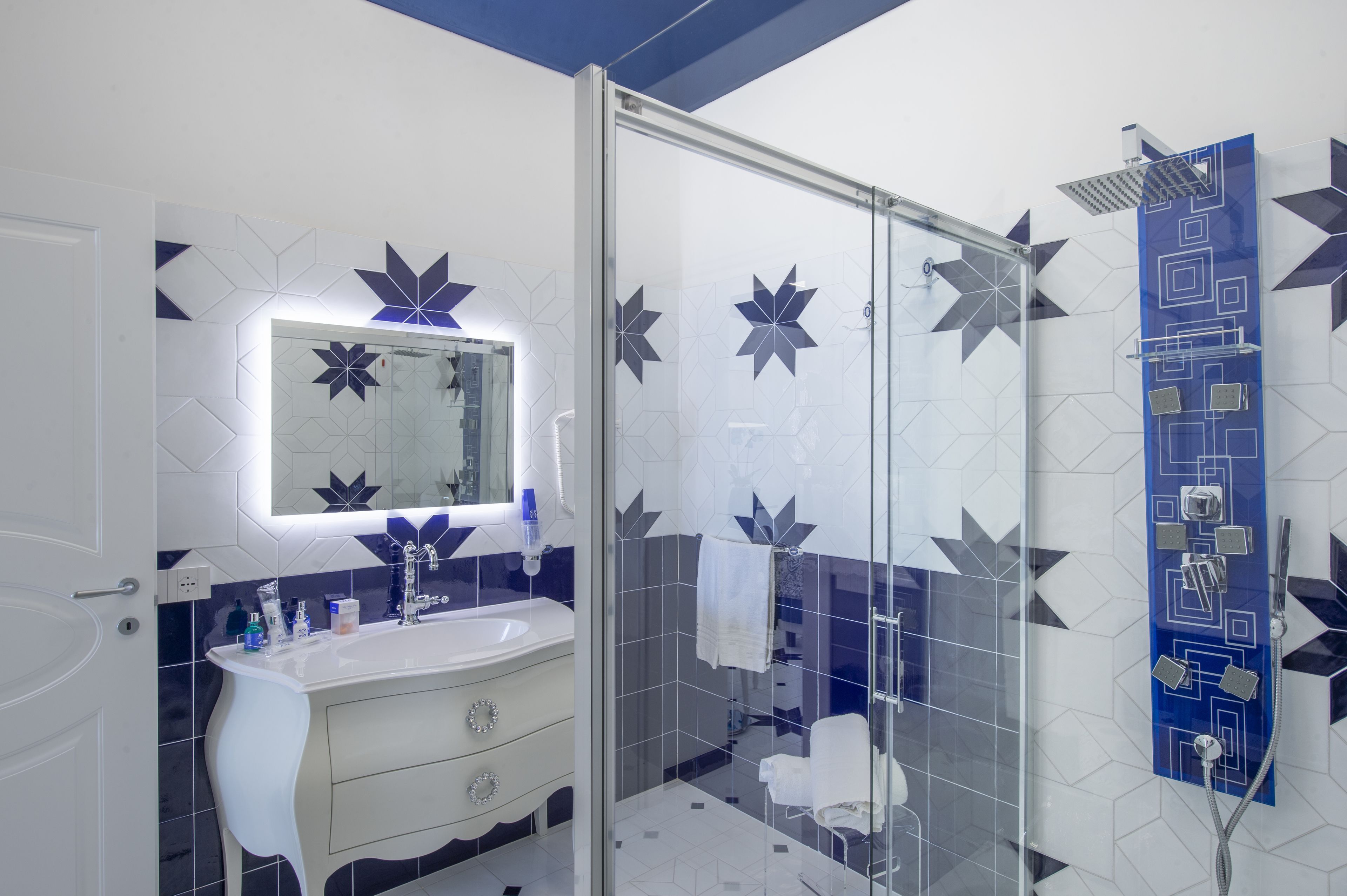 A bathroom with a white sink, mirror, and glass shower enclosure.