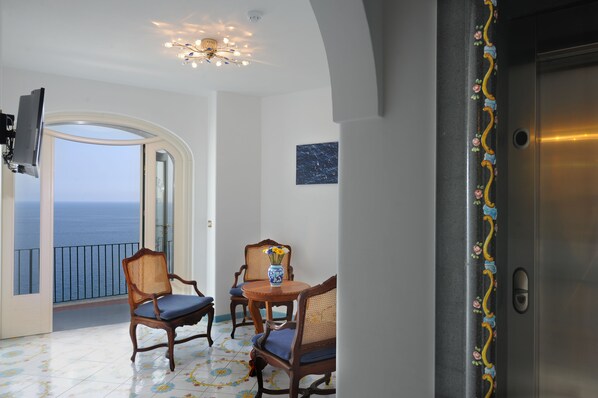 A balcony with a view of the sea, a dining table with chairs, and a decorative vase. - Hotel Villa Maria Pia (Praiano)
