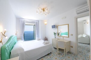 Habitación de hotel con una cama grande, un escritorio, una silla, un espejo y vistas al mar.