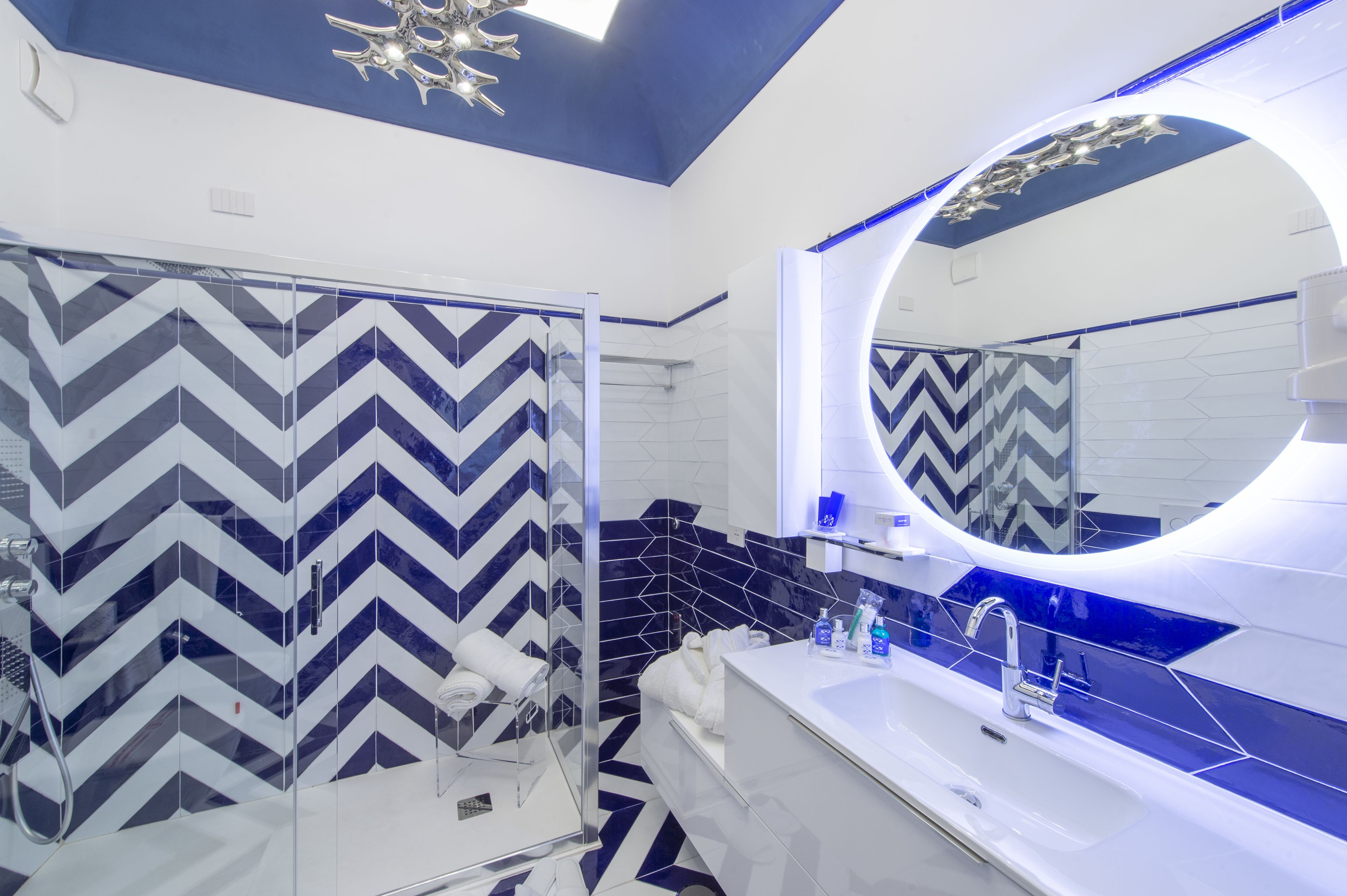 Un baño moderno con ducha, un espejo grande y un lavabo blanco.